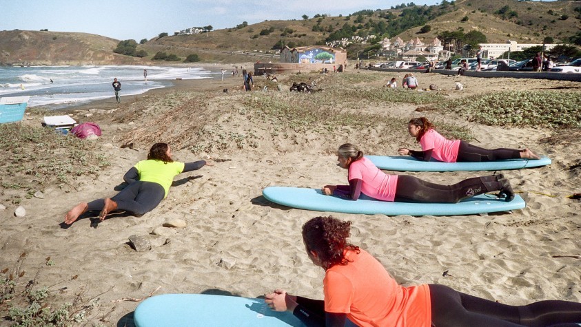 Three people in a surfing lesson on the beach