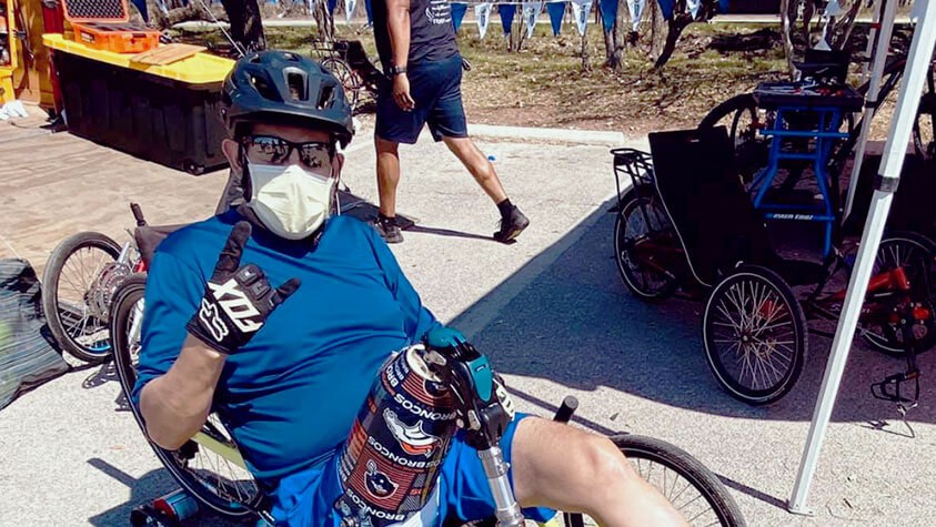 A cyclist with a Denver Broncos prosthetic gives their ride a thumbs up.