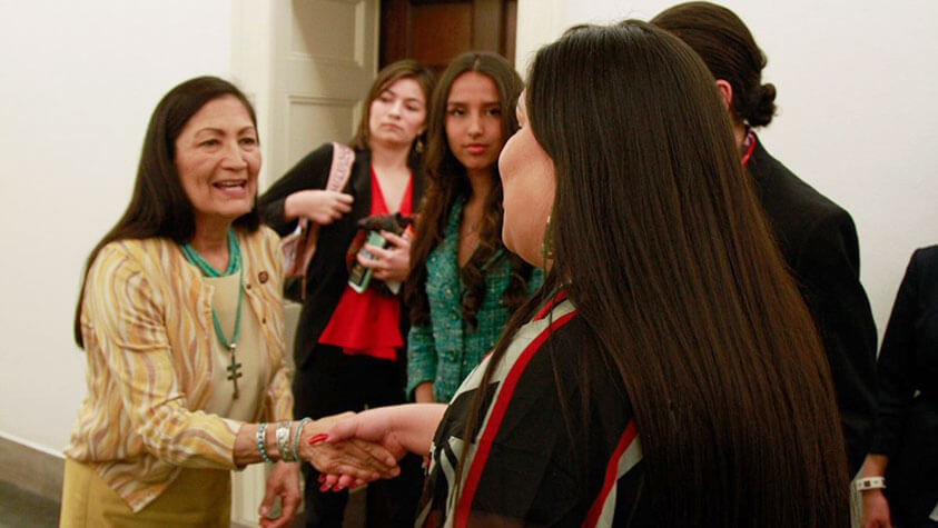 A group of youths shake the hand of Deb Haaland, Secretary of the Interior, in her office at the US capitol building.