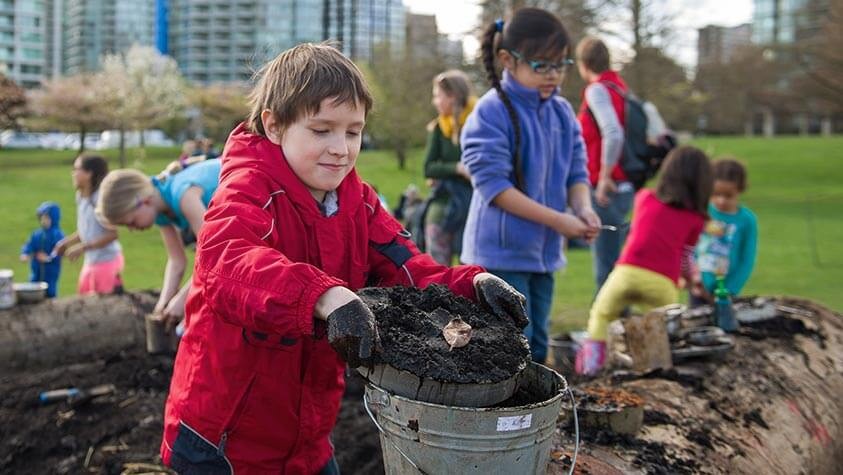 At a city park, children happily sift through dirt in search of nature's secrets.