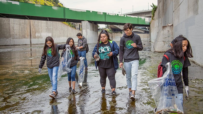 A group of children walk the Los Angeles River to help clean up debris.