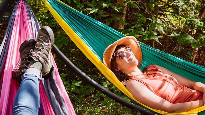 After the day's hike, two friends recharge in hammocks under shadow dappled afternoon sun.