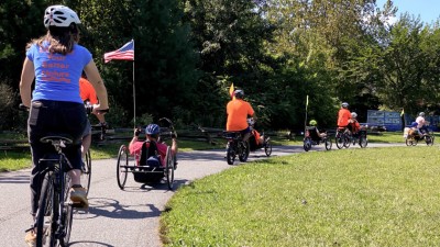 Group of cyclers on two wheel and recumbent trikes exploring a bike path.