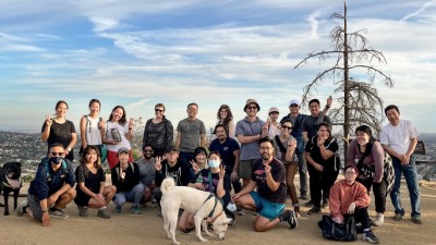 A group of approximately two dozen people smiling on a trail overlook