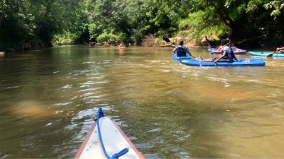 A large group of diverse people kayaking down the South River in the Upper Ocmulgee Basin.