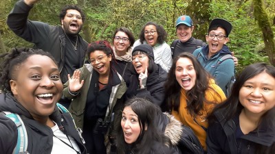 Against a backdrop of verdant woodland, a group of friends smile broadly for a mid-hike photo op.