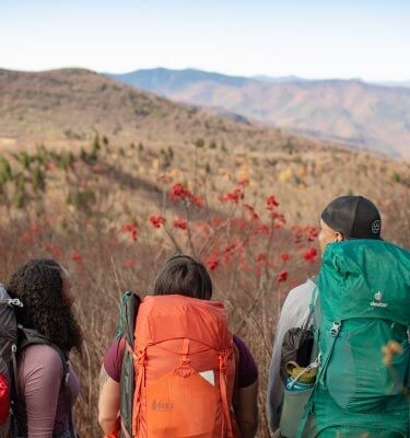 Under a sunny morning sky, four friends embark on a multi-day fall hike.