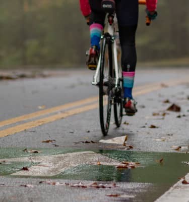 After a spring rain, a cyclist rides past runners on a shared urban path.