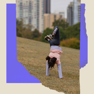 A youngster practices their handstand in a city park.