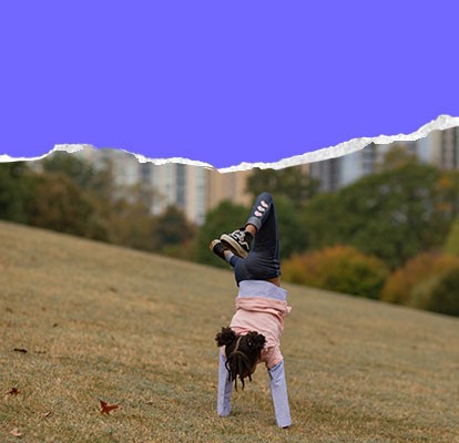 A youngster practices their handstand in a city park.